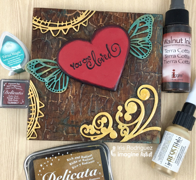 Wooden wall hanging with a your are loved sentiment on a flying clay heart made with Tsukineko and Imagine color products.